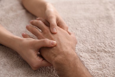 Photo of Man receiving hand massage on soft towel, closeup