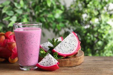 Photo of Delicious pitahaya smoothie and fresh fruits on wooden table, space for text