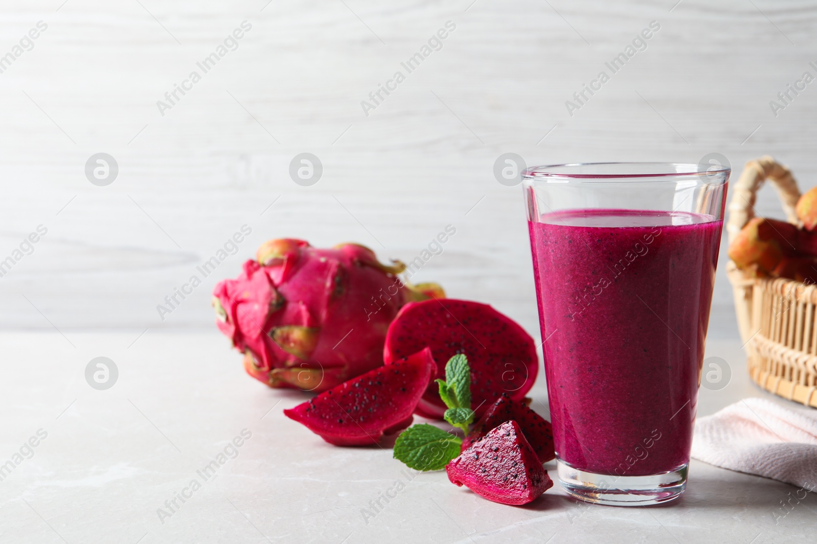 Photo of Delicious pitahaya smoothie and fresh fruits on light grey table, space for text