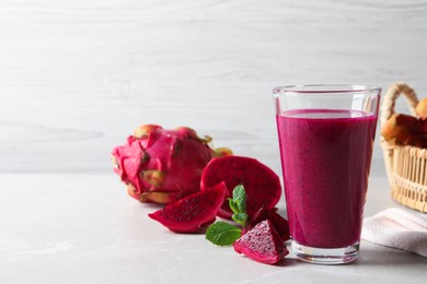 Photo of Delicious pitahaya smoothie and fresh fruits on light grey table, space for text