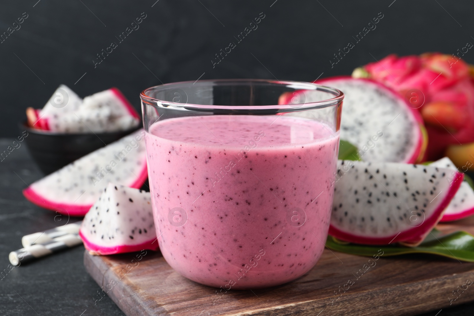 Photo of Delicious pitahaya smoothie and fresh fruits on black table, closeup