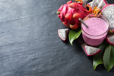 Photo of Delicious pitahaya smoothie and fresh fruits on black table, space for text