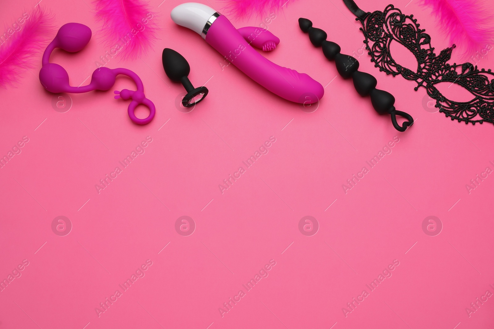 Photo of Sex toys, feather and black lace mask on pink background, flat lay. Space for text