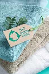 Photo of Stacked towels with recycling label and plant, closeup