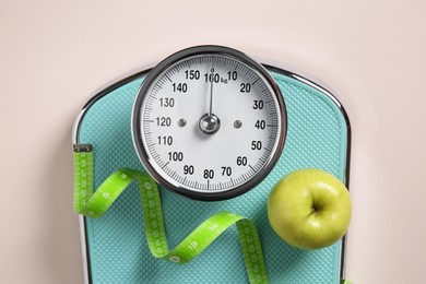 Photo of Scale, measuring tape and fresh apple on beige background, top view