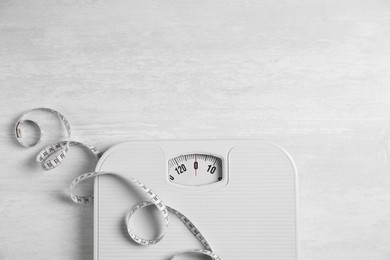 Photo of Scale and measuring tape on white wooden background, flat lay. Space for text