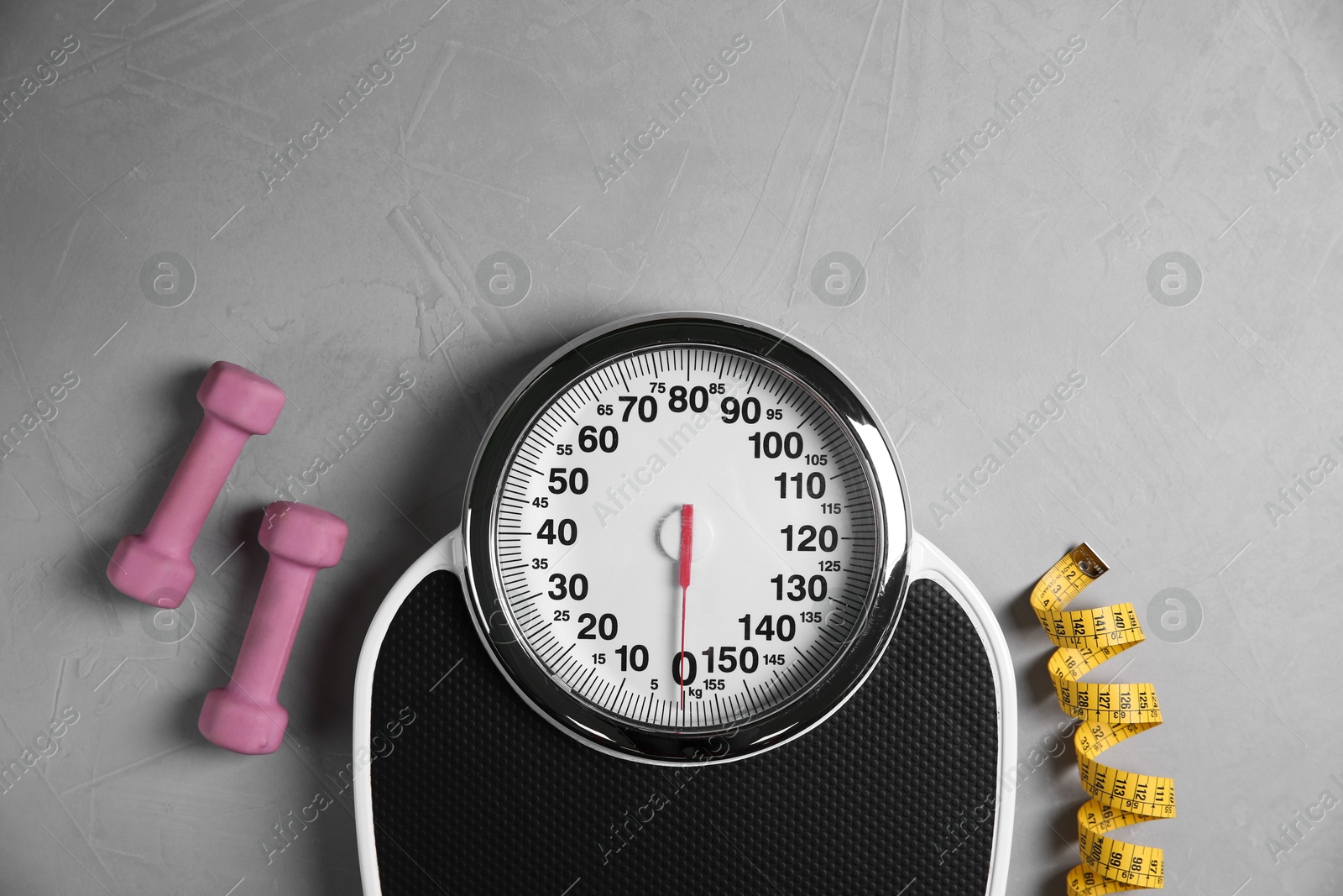 Photo of Bathroom scale, measuring tape and dumbbells on grey textured background, flat lay