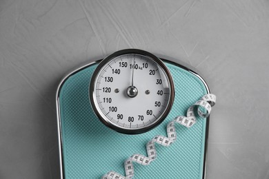 Photo of Scale and measuring tape on grey textured background, top view