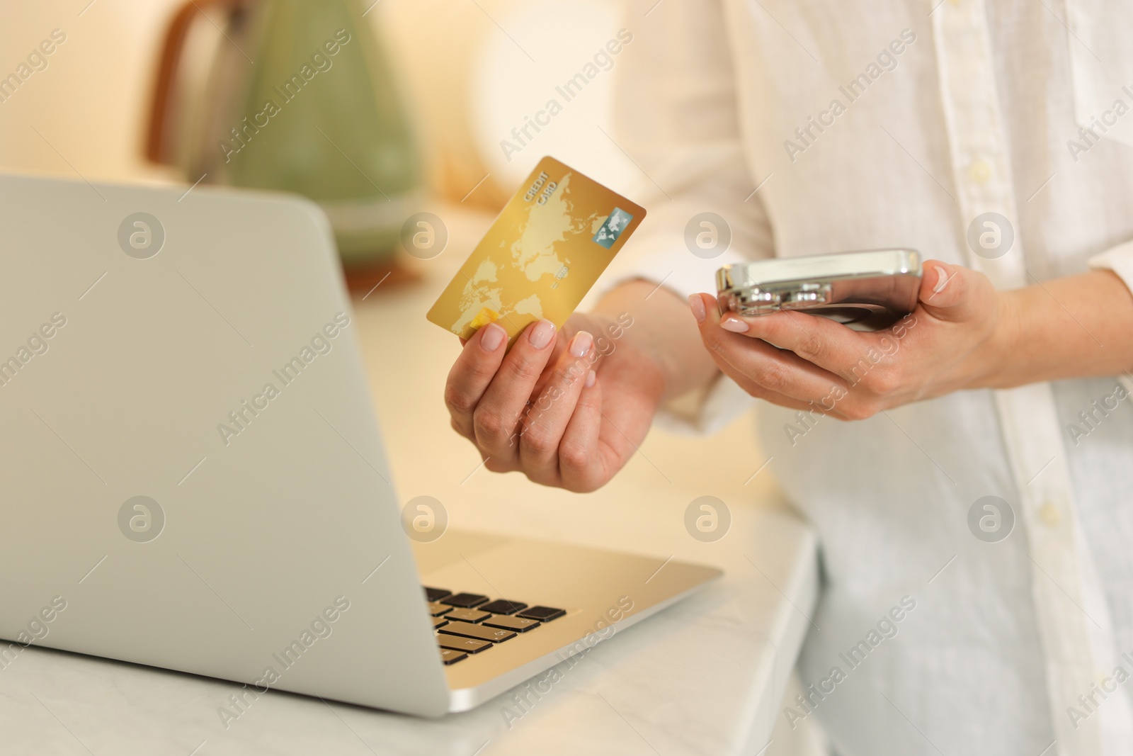 Photo of Online banking. Woman with credit card, smartphone and laptop paying purchase at white table, closeup