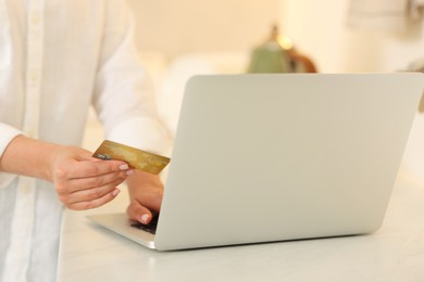 Photo of Online banking. Woman with credit card and laptop paying purchase at white table, closeup