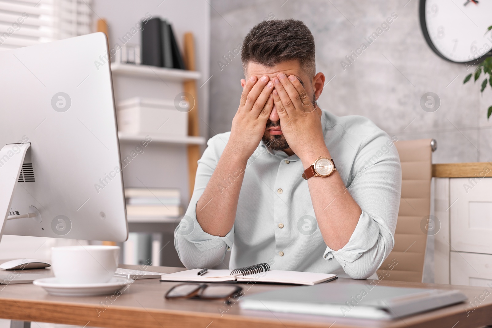 Photo of Overwhelmed man sitting at table in office