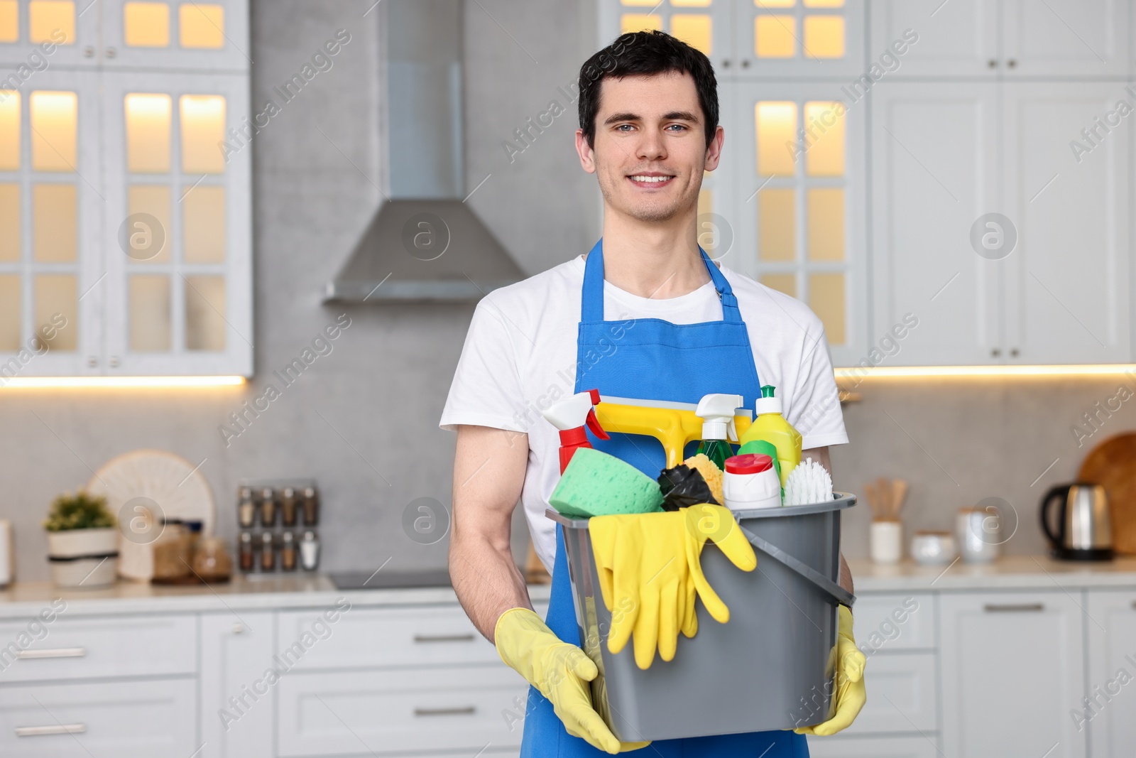 Photo of Cleaning service worker holding bucket with supplies in kitchen