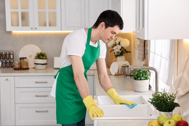 Photo of Professional janitor cleaning sink with rag in kitchen
