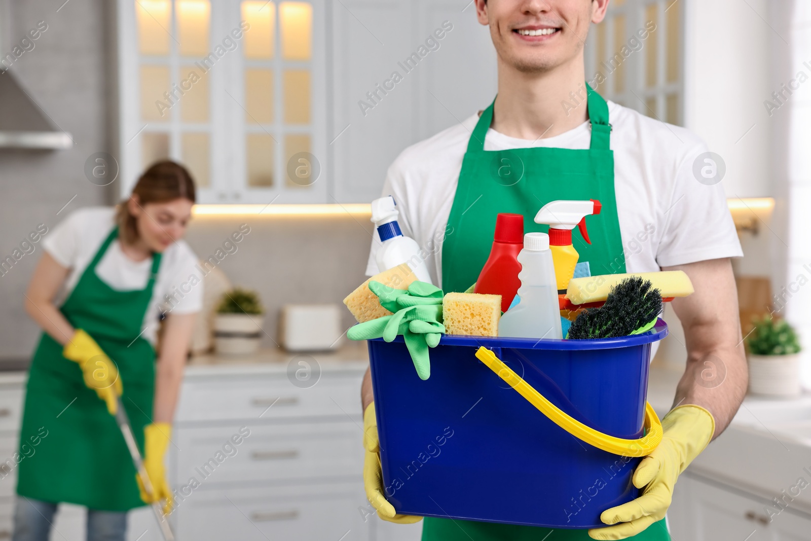 Photo of Cleaning service worker holding bucket with supplies in kitchen