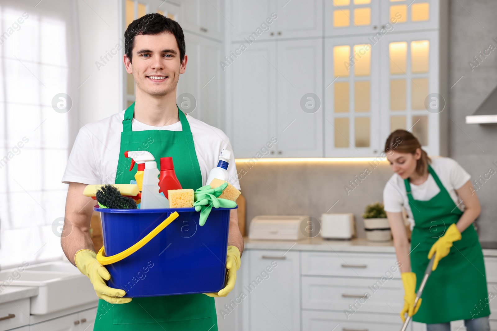 Photo of Cleaning service worker holding bucket with supplies in kitchen