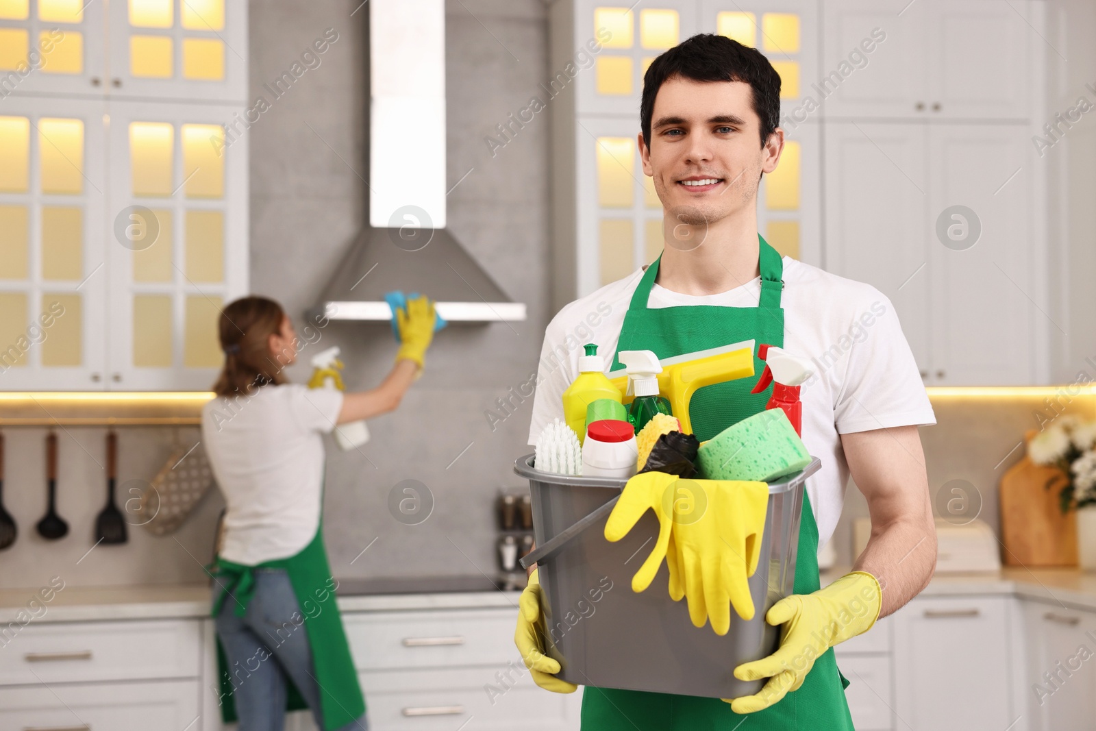 Photo of Cleaning service worker holding bucket with supplies in kitchen