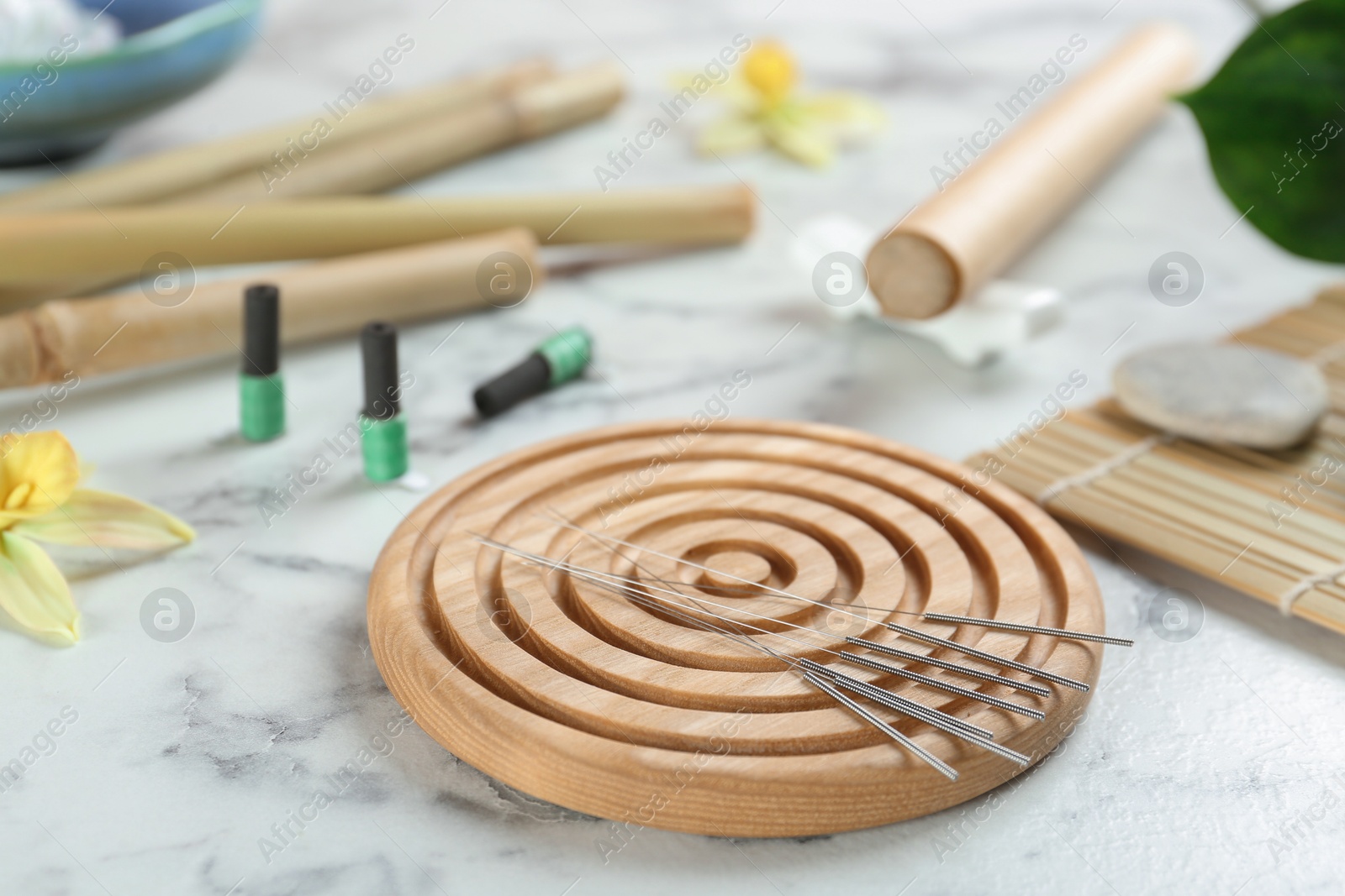 Photo of Wooden coaster with acupuncture needles on white marble table