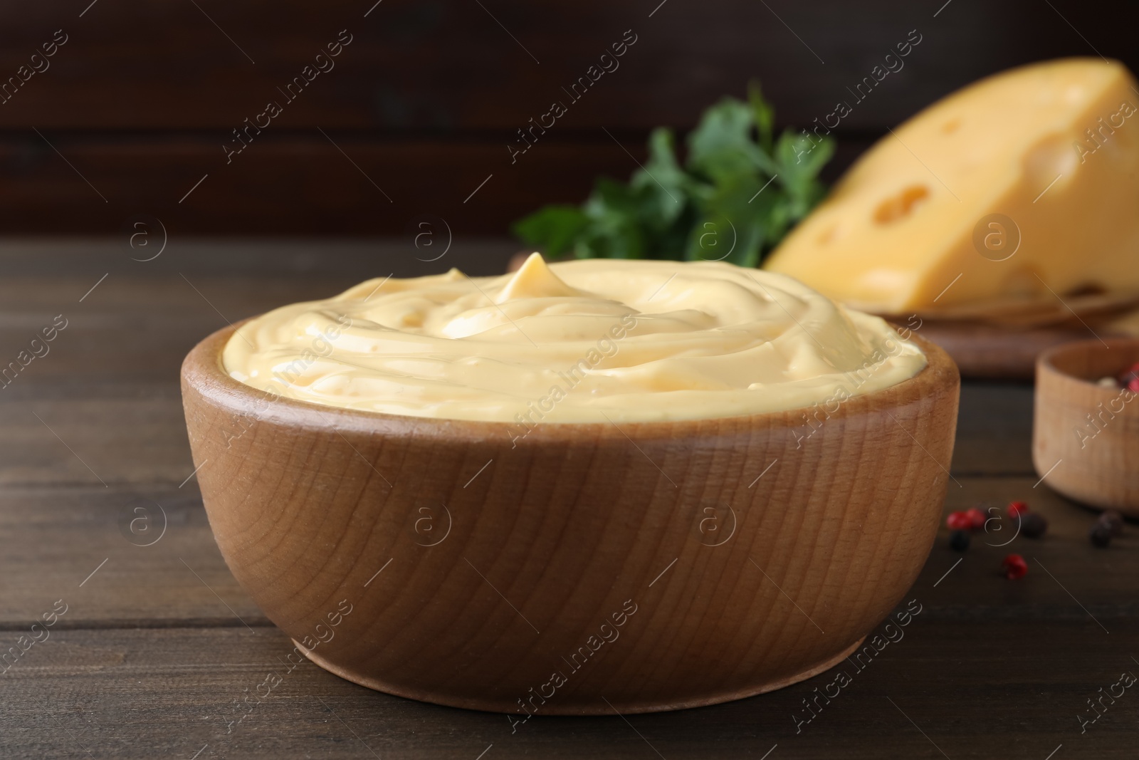 Photo of Tasty cheese sauce in bowl on wooden table, closeup