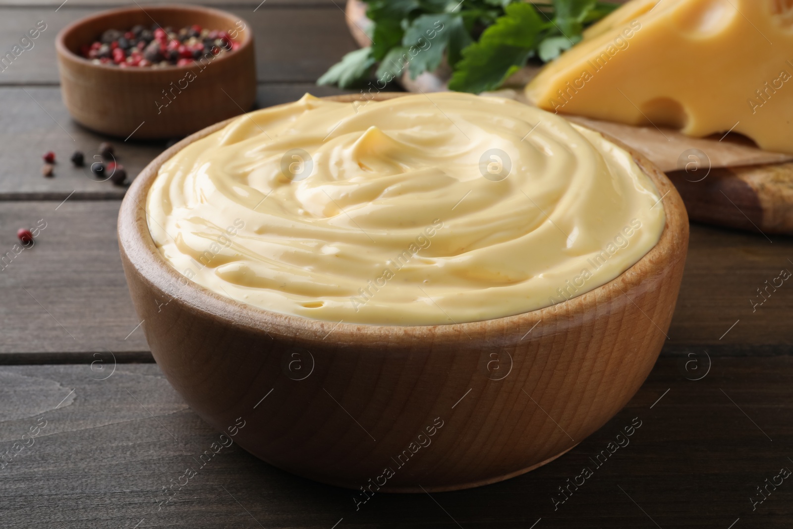 Photo of Tasty cheese sauce in bowl on wooden table, closeup