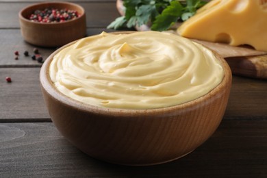 Photo of Tasty cheese sauce in bowl on wooden table, closeup