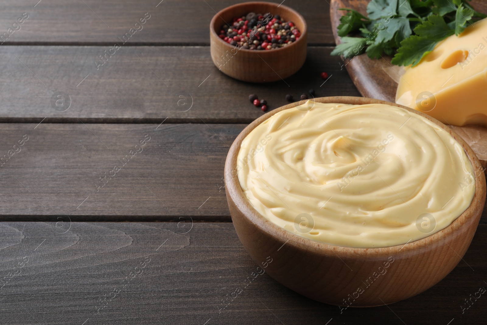 Photo of Tasty cheese sauce in bowl on wooden table, space for text