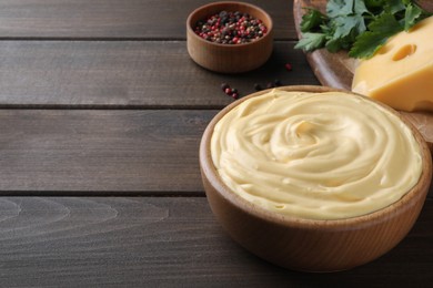 Photo of Tasty cheese sauce in bowl on wooden table, space for text