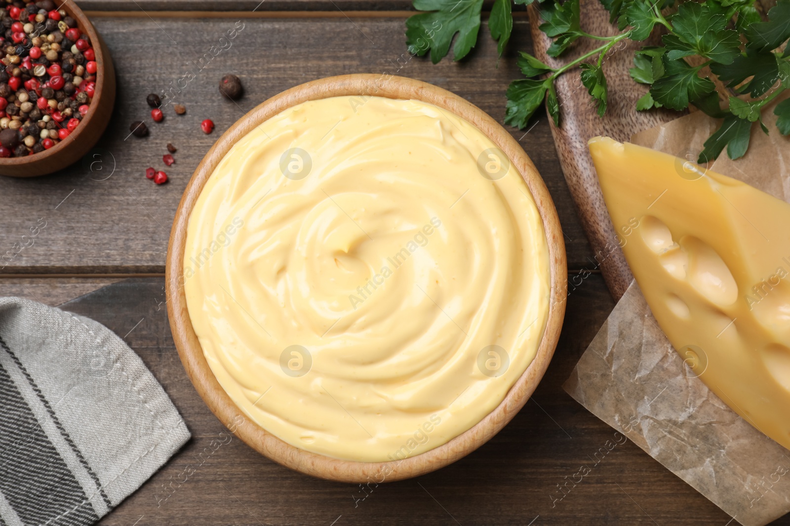 Photo of Tasty cheese sauce, pepper and parsley on wooden table, flat lay