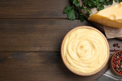 Photo of Tasty cheese sauce, pepper and parsley on wooden table, flat lay. Space for text