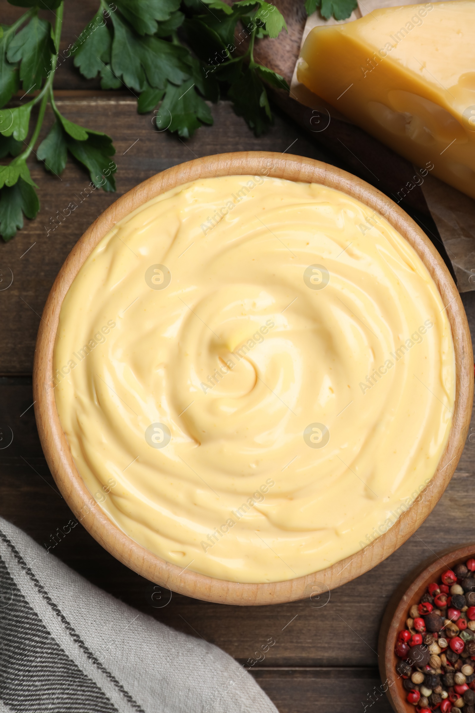 Photo of Tasty cheese sauce, pepper and parsley on wooden table, flat lay