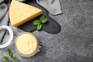 Tasty cheese sauce and basil on grey table, flat lay. Space for text