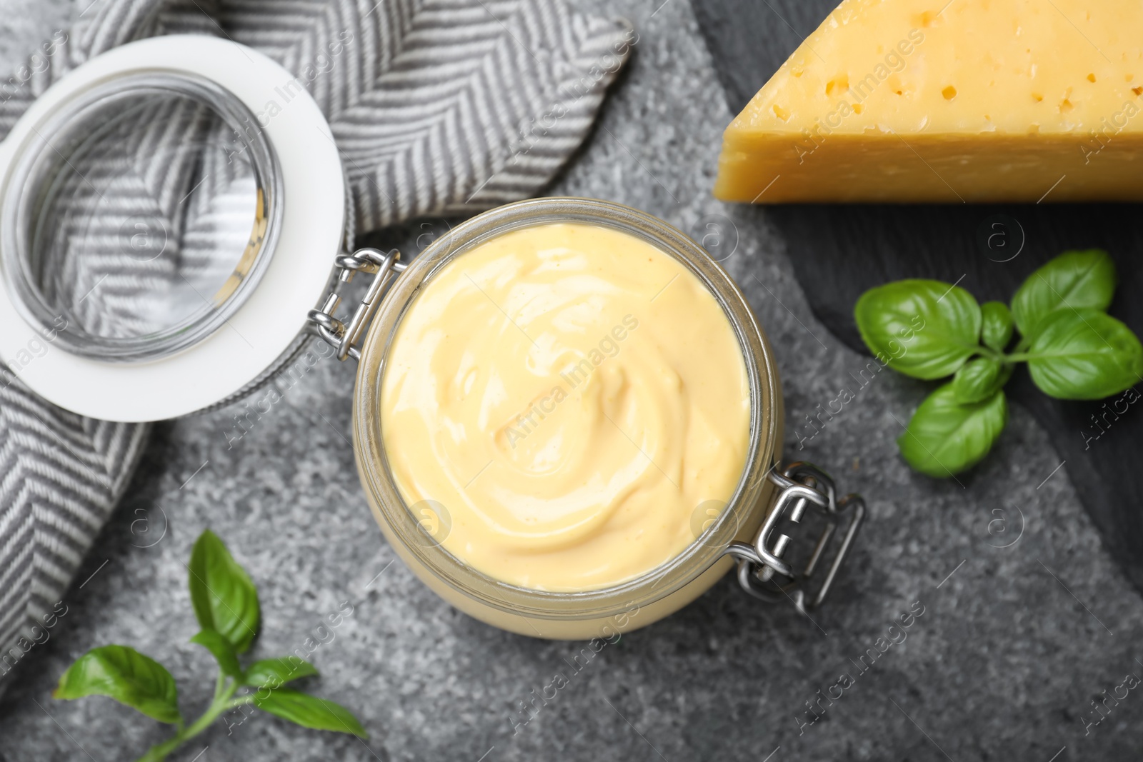 Photo of Tasty cheese sauce and basil on grey table, flat lay