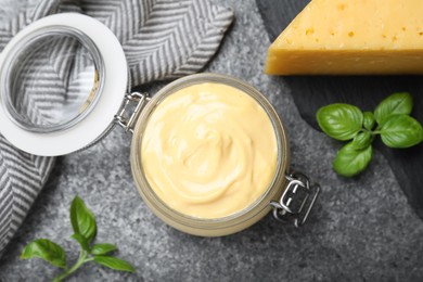 Tasty cheese sauce and basil on grey table, flat lay