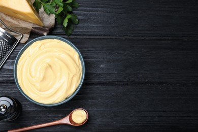 Photo of Tasty cheese sauce and parsley on black wooden table, flat lay. Space for text