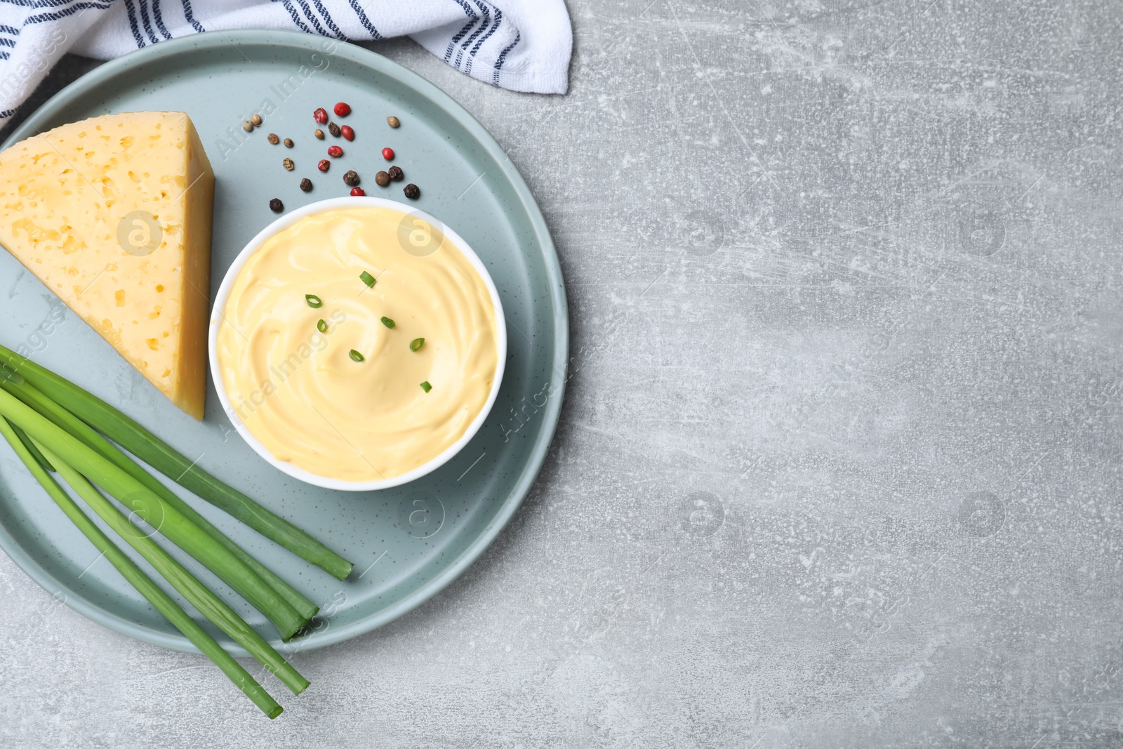 Photo of Tasty cheese sauce with green onion and peppercorns on light grey table, top view. Space for text