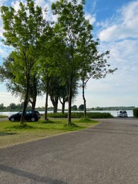 Beautiful view on embankment with trees and parked cars near lake