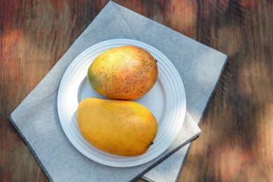 Photo of Plate with tasty mangoes on wooden table outdoors, top view