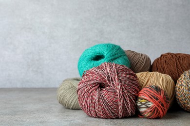 Photo of Many different soft woolen yarns on grey table, space for text