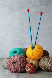 Photo of Soft woolen yarns and knitting needles on grey table