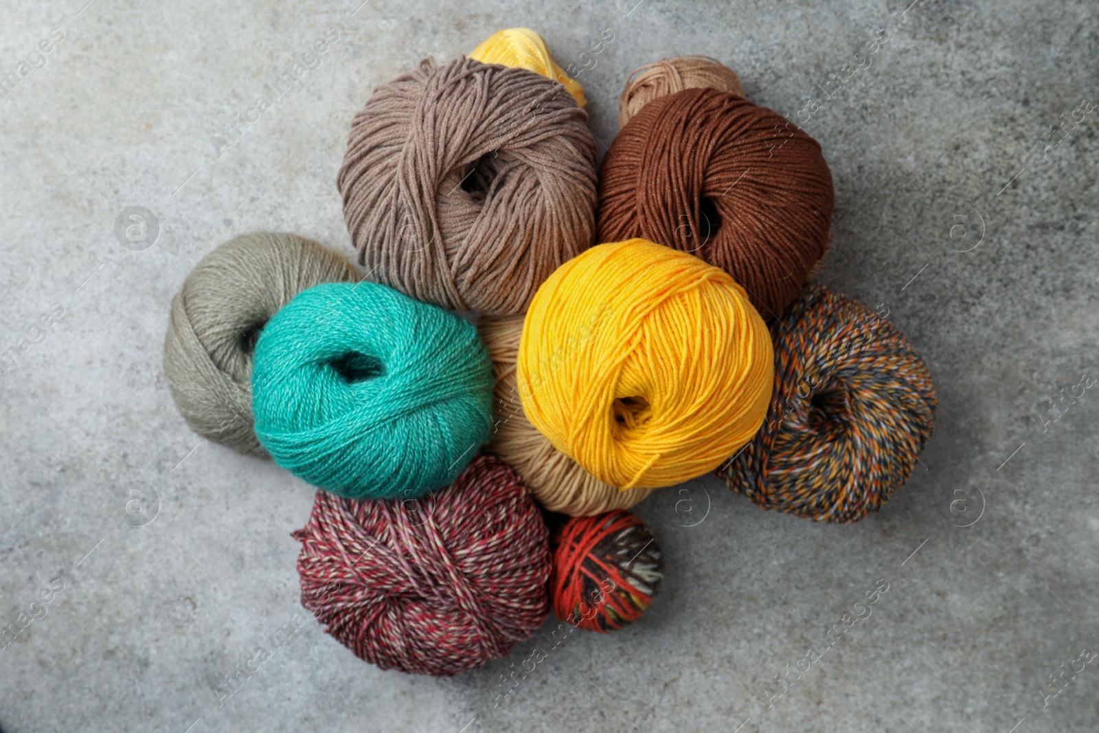 Photo of Many different soft woolen yarns on grey table, flat lay