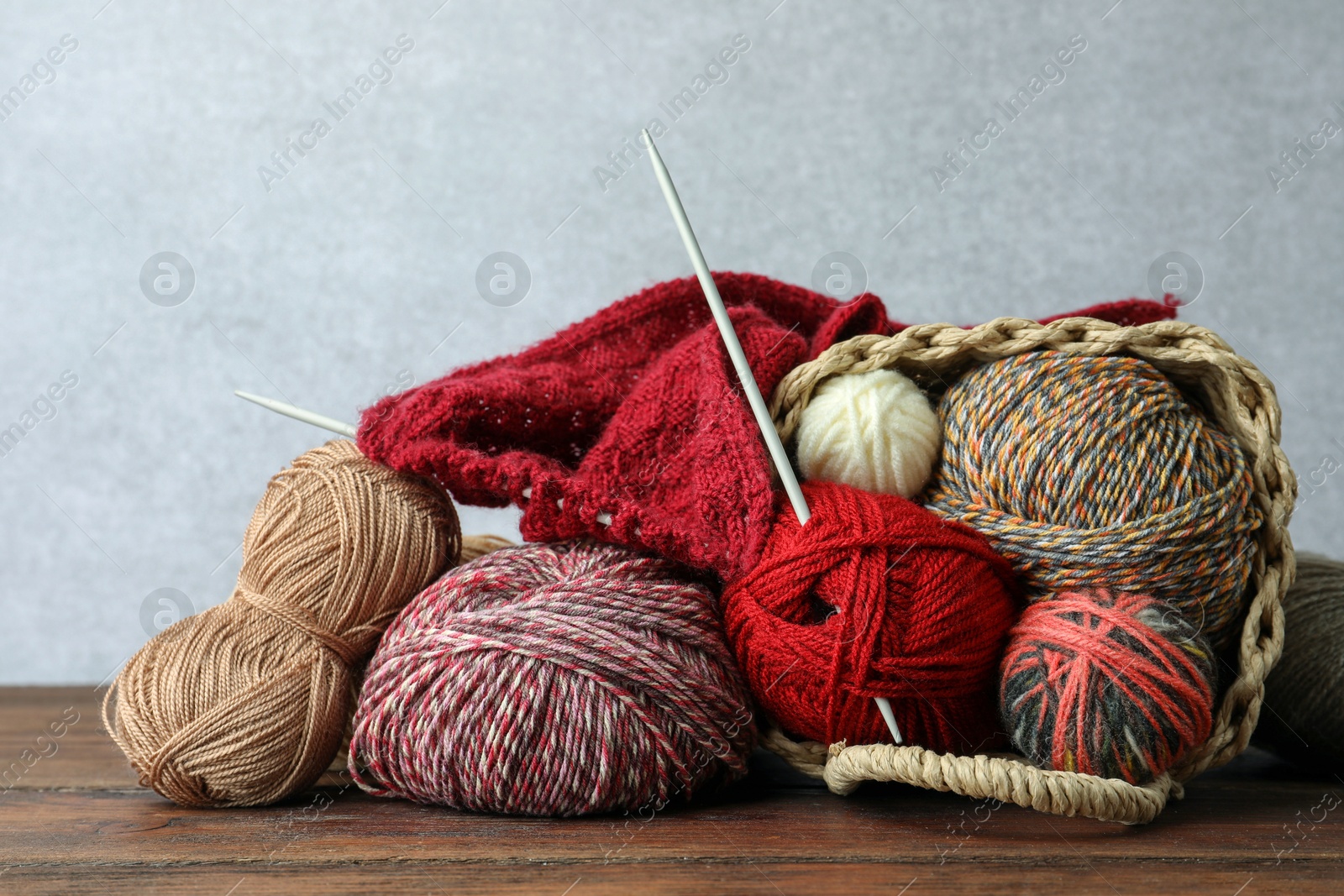 Photo of Soft woolen yarns, knitting and needles on wooden table