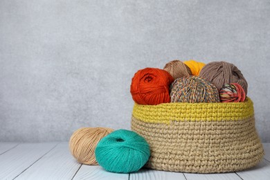 Soft woolen yarns on white wooden table, space for text