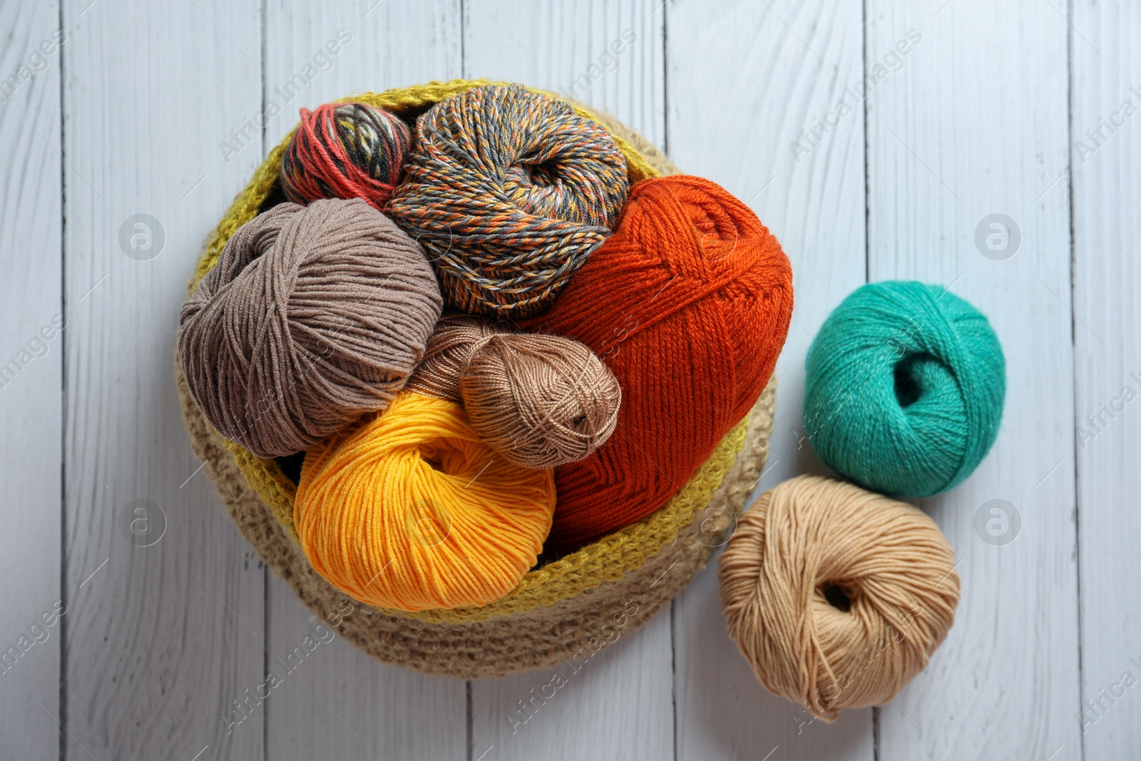 Photo of Soft woolen yarns on white wooden table, flat lay