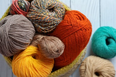 Soft woolen yarns on white wooden table, closeup