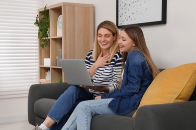 Photo of Happy mother and her teenage daughter with laptop at home