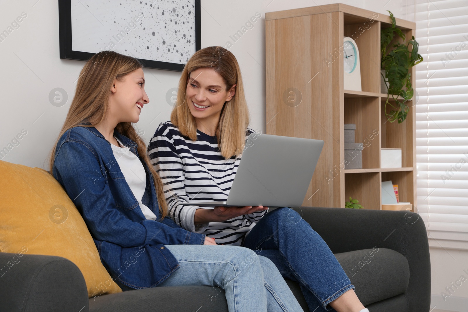 Photo of Happy mother and her teenage daughter with laptop at home