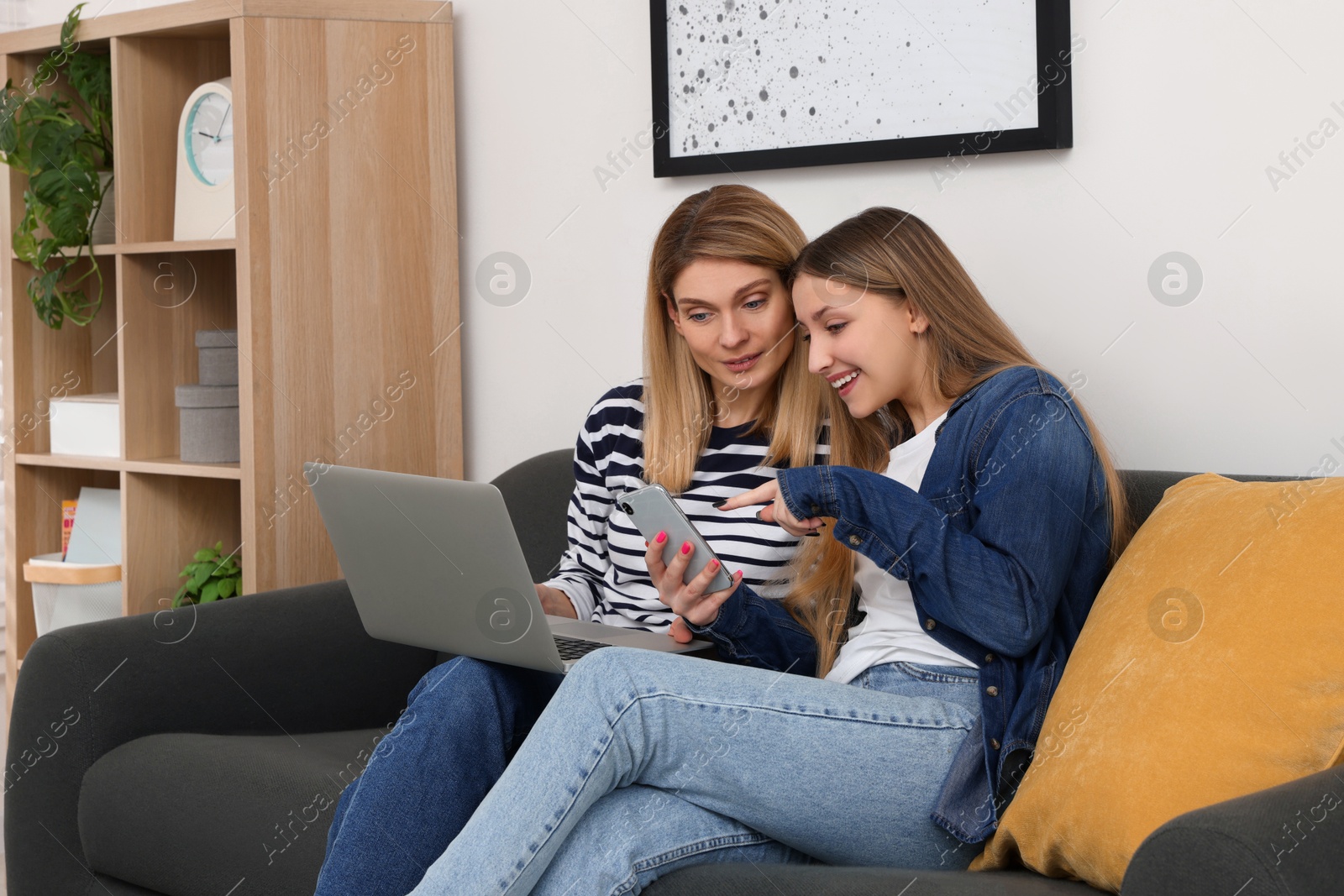 Photo of Happy mother and her teenage daughter with devices spending time together at home
