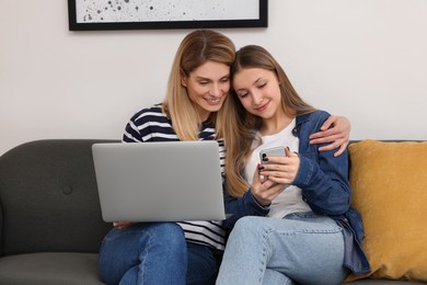Photo of Happy mother and her teenage daughter with devices spending time together at home