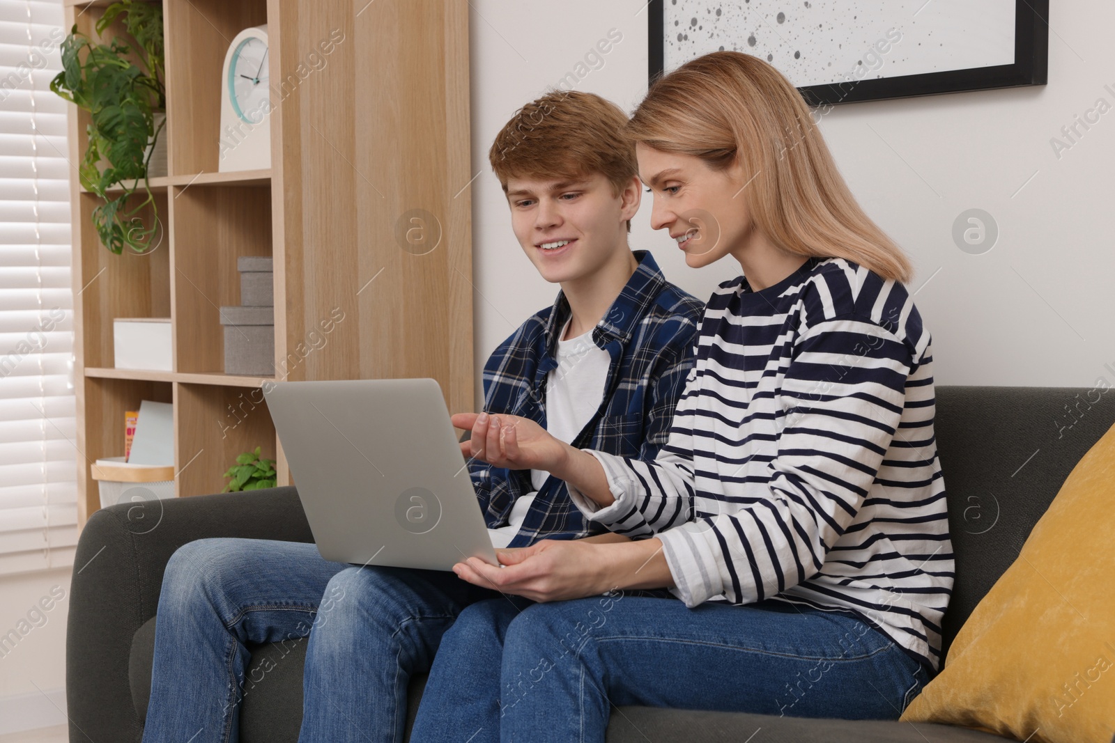 Photo of Happy mother and her teenage son with laptop at home