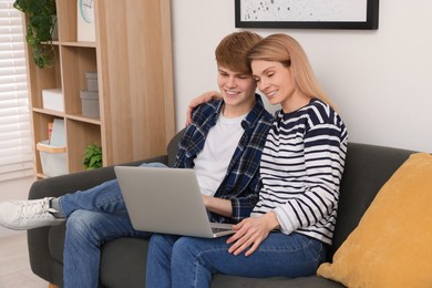 Photo of Happy mother and her teenage son with laptop at home