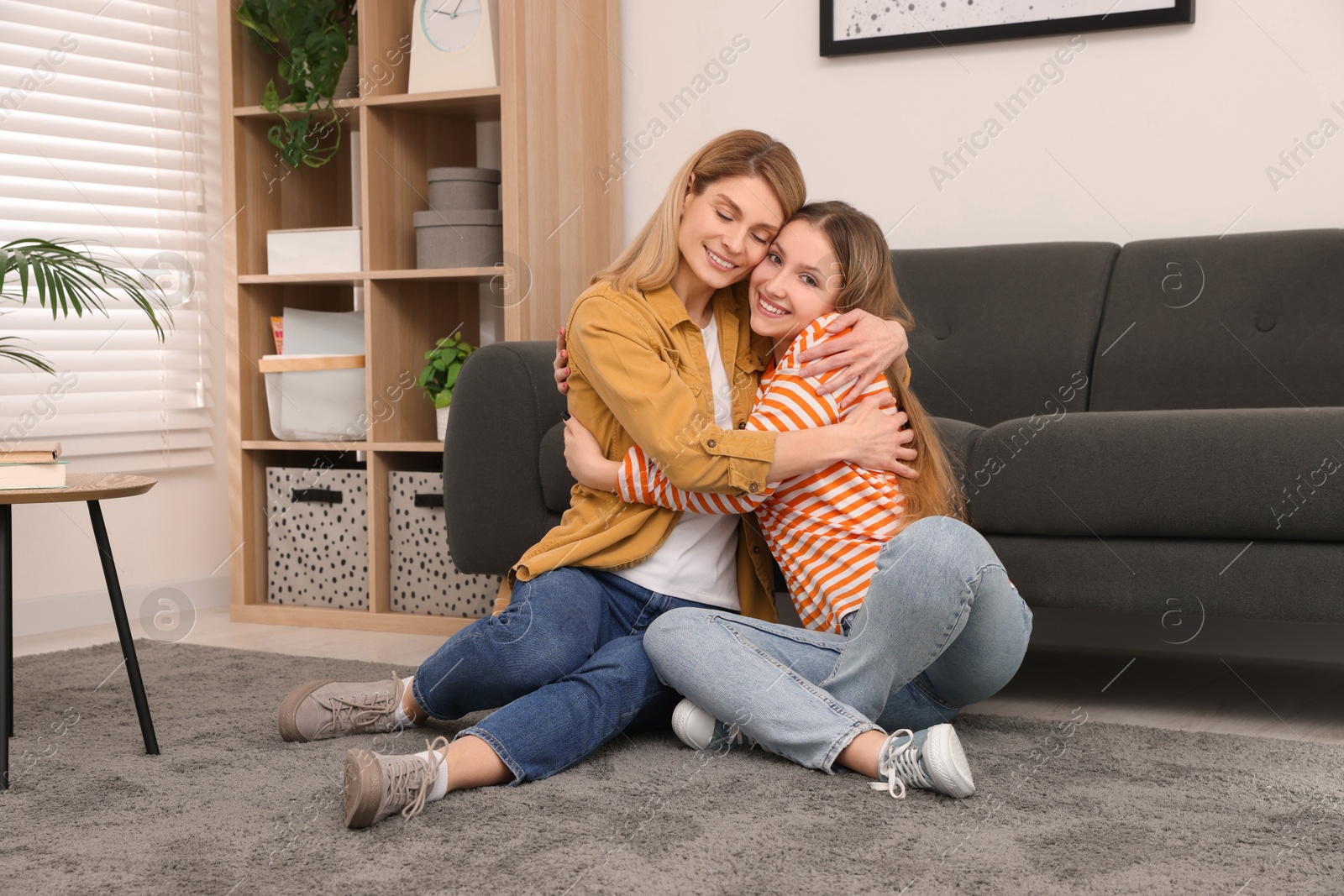 Photo of Happy mother hugging her teenage daughter on floor at home